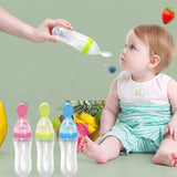 Pink baby squeeze feeding bottle standing upright on a highchair tray using its suction cup base.