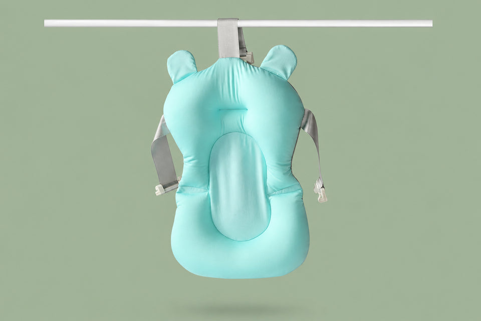 Newborn baby comfortably reclining on a floating bath cushion in a sink