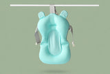 Newborn baby comfortably reclining on a floating bath cushion in a sink