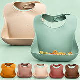 Soft waterproof silicone baby bib with a deep food catcher pocket catching spilled food.